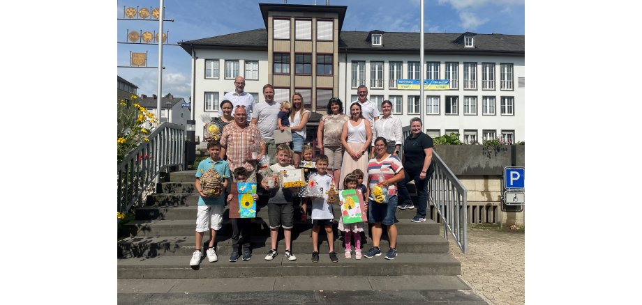 Zahlreiche Erwachsene und Kinder stehen auf der Treppe vor dem Rathaus - einige haben verschiedene Preise in der Hand