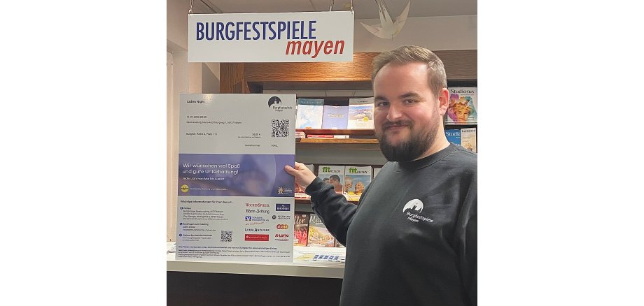 Verwaltungsleiter Kevin Stoye vor einem Plakat zu dem neuen Ticketsystem