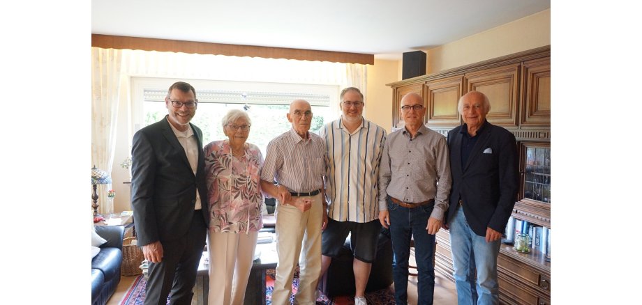 6 Personen stehen in einem Wohnzimmer für ein Foto zusammen