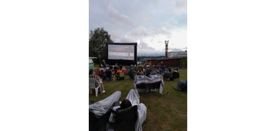 Viele Personen mit Campingstühlen im Open-Air KIno