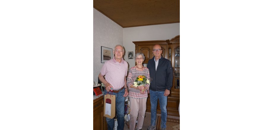 2 Männer und eine Frau in der Mitte mit einem Blumenstrauß