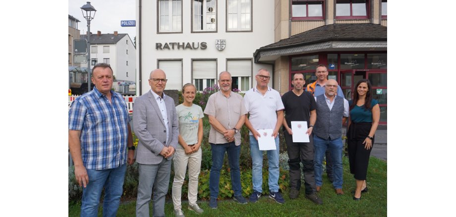 9 Personen stehen vor dem Rathaus