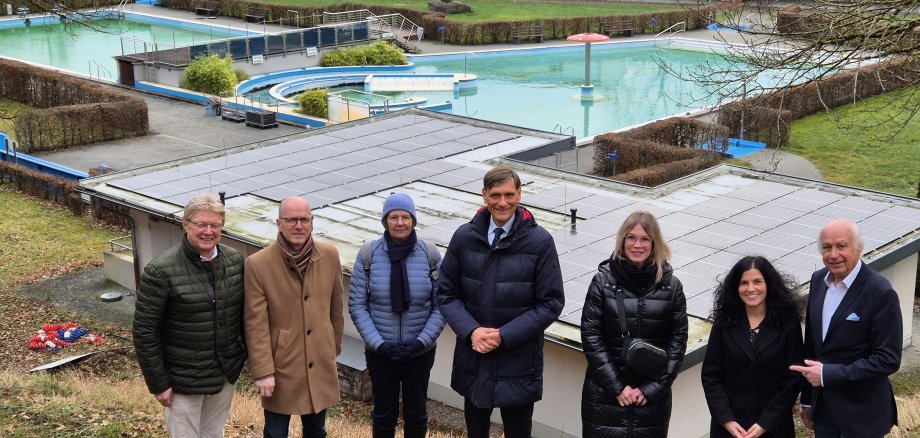 7 Personen stehe vor einem Schwimmbad für ein Foto zusammen